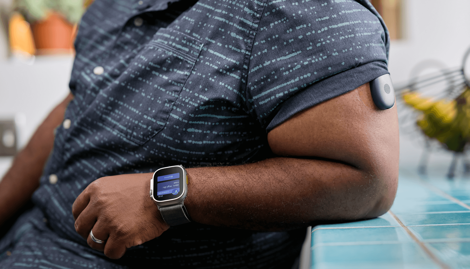 Ein Eversense-Benutzer tr&auml;gt eine Smartwatch, die Blutzuckerdaten anzeigt, mit einem Blutzuckermessger&auml;t am Arm.