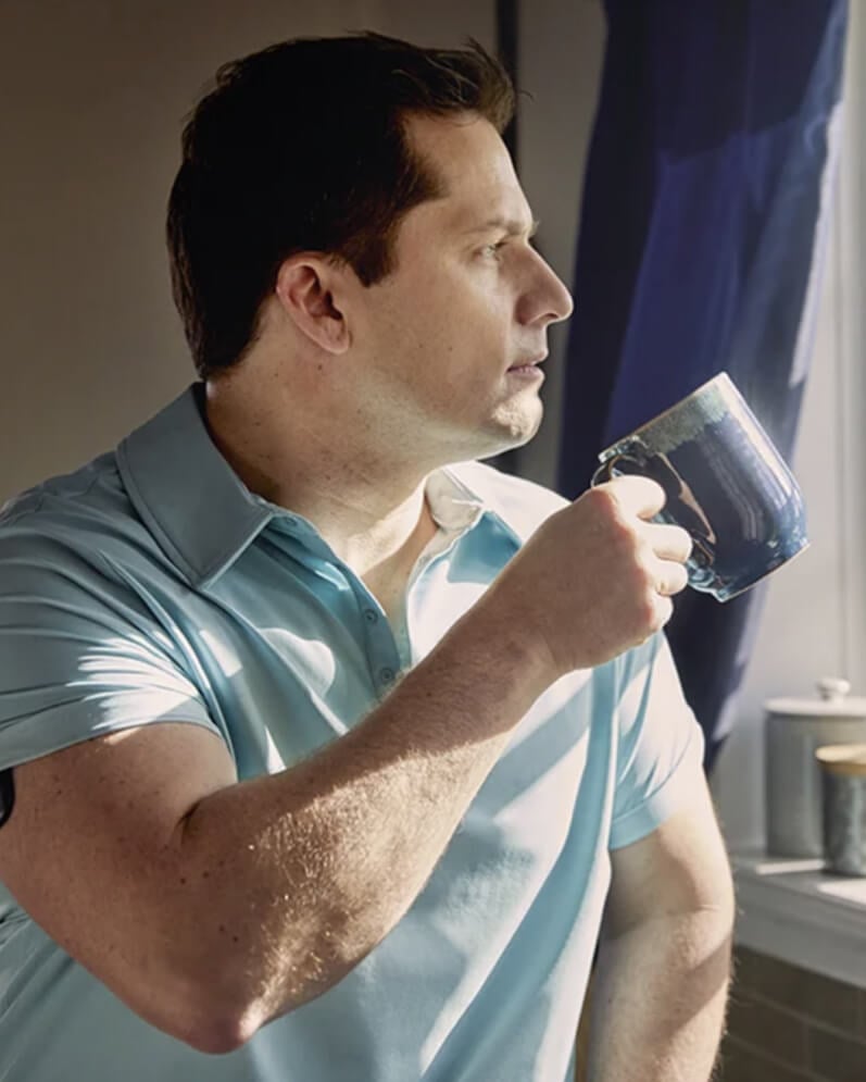 Ein Eversense CGM Benutzer hält einen blaue Tasse und trägt den Eversense Transmitter am Arm.