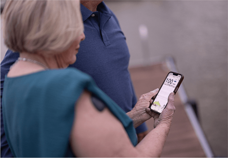 Eine ältere Frau prüft ihr Smartphone zur Überwachung des Glukosespiegels.