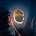 Eine Eversense Benutzerin reist mit einem CGM-Gerät, während sie einen Hut trägt und entspannt aus dem Flugzeugfenster blickt.